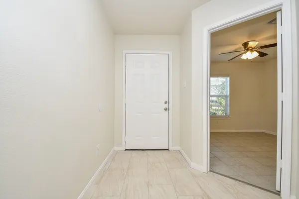 an empty room with kitchen view and a chandelier
