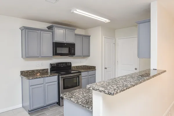 a kitchen with granite countertop a sink stove and cabinets