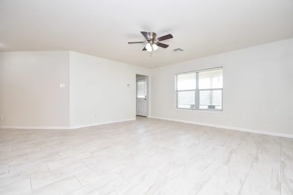 an empty room with a window and a ceiling fan