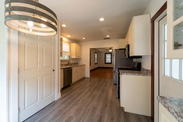 a view of a kitchen center island wooden floor and stainless steel appliances