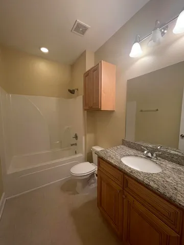 a bathroom with a granite countertop sink a toilet and bathtub