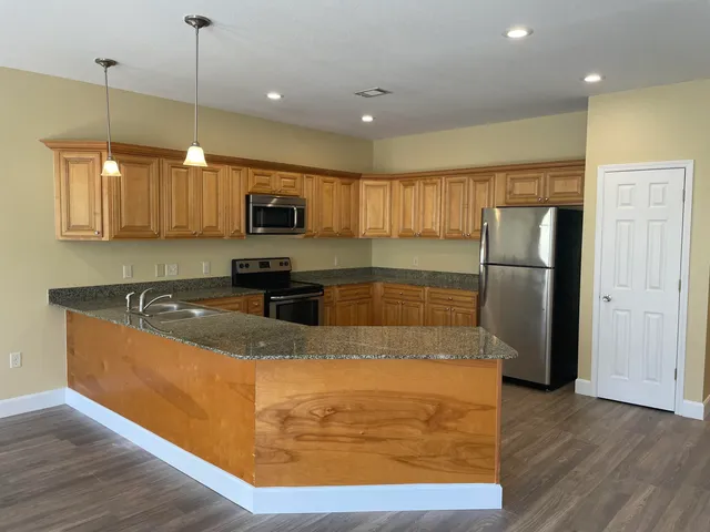 a kitchen with stainless steel appliances granite countertop a refrigerator a sink a stove a microwave and wooden floors