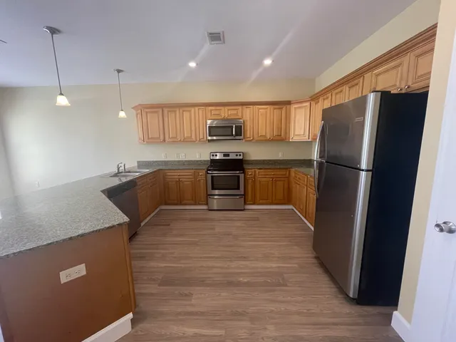 a kitchen with stainless steel appliances granite countertop a refrigerator a sink a stove and a refrigerator