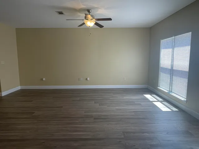 a view of a room with wooden floor and a ceiling fan