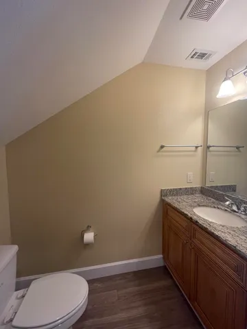 a bathroom with a granite countertop toilet and a sink