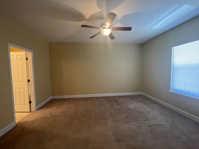 an empty room with a chandelier fan and windows