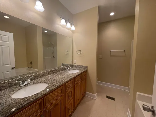 a bathroom with a granite countertop double vanity sink and a mirror