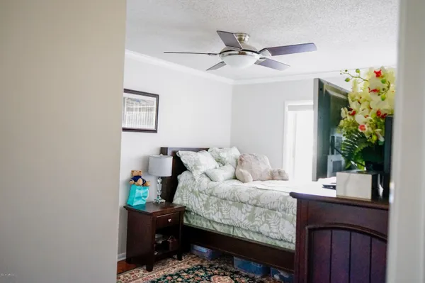 a bedroom with a bed a potted plant on the dresser and a window