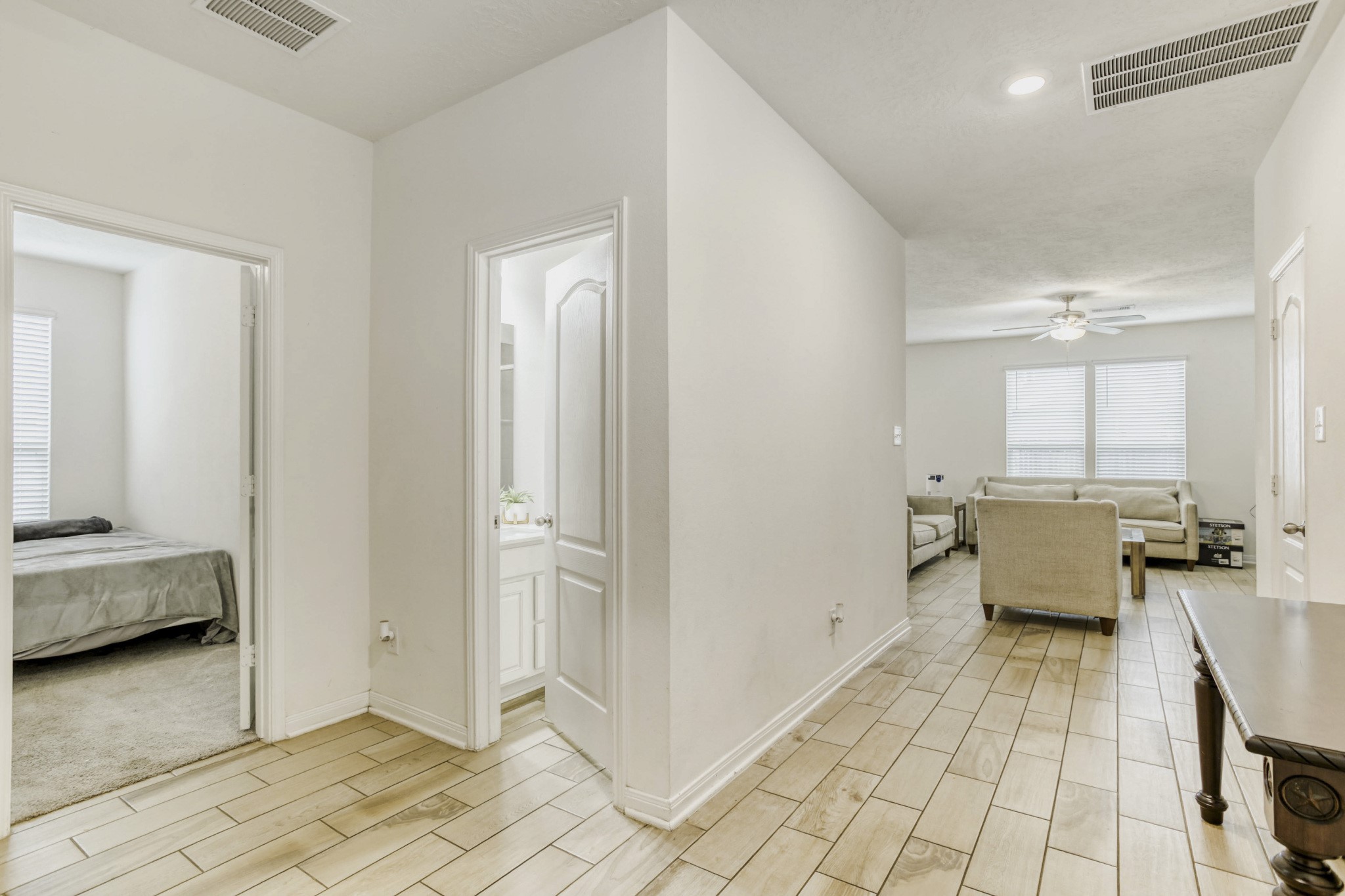 3331 Forest Chitto Dr Spring Spring, TX 77373 - Photo 4 of 29 This photo features a big and bright tiled hallway leading to a cozy living room. There’s a bedroom on the left and a bathroom on the right, showcasing a practical layout with ample natural light.
