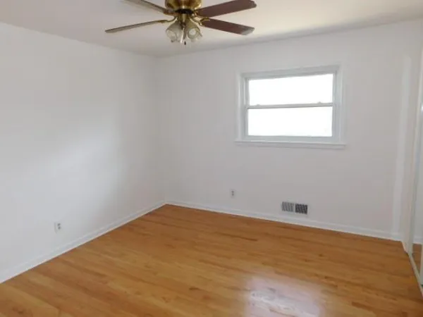 an empty room with a window and a fan