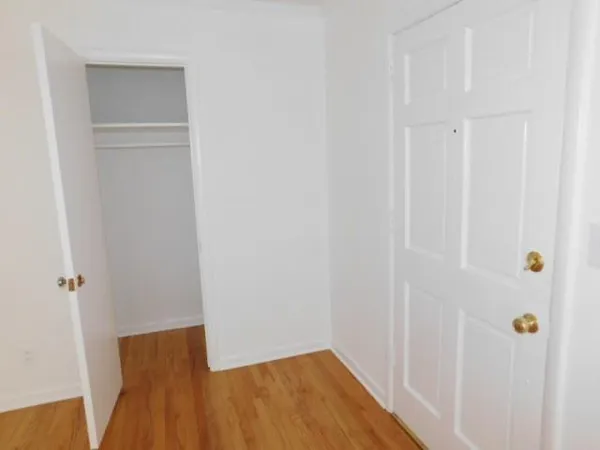 a view of a hallway with wooden floor and closet