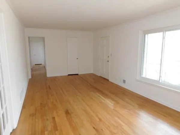 a big room with wooden floor and windows in a room