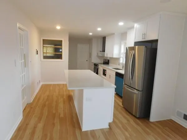 a kitchen with stainless steel appliances a refrigerator and wooden floor