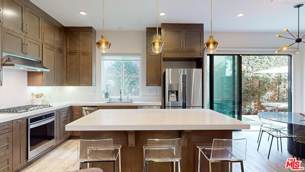 20607 West Chestnut Circle Porter Ranch, CA 91326 - Photo 5 of 52 a kitchen with stainless steel appliances a stove a refrigerator a sink and a dining table