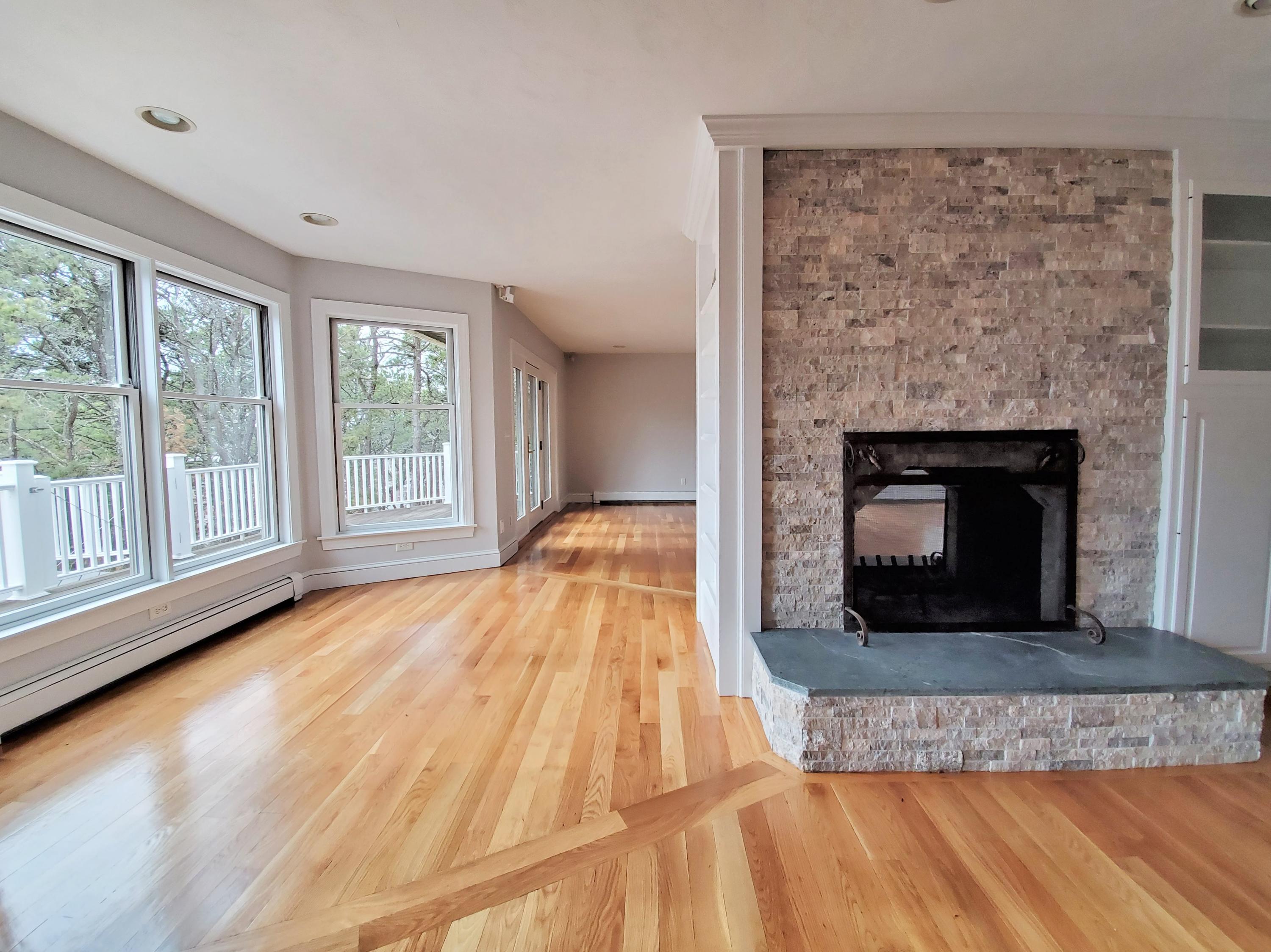 50 Major Doane Road Wellfleet, MA 02667 - Photo 13 of 91 a living room with a fireplace and a floor to ceiling window