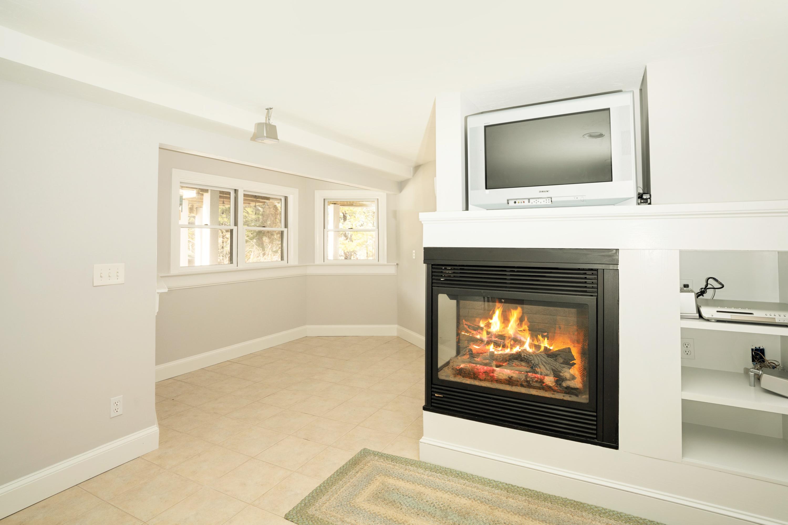 50 Major Doane Road Wellfleet, MA 02667 - Photo 50 of 91 a living room with a fireplace and a flat screen tv