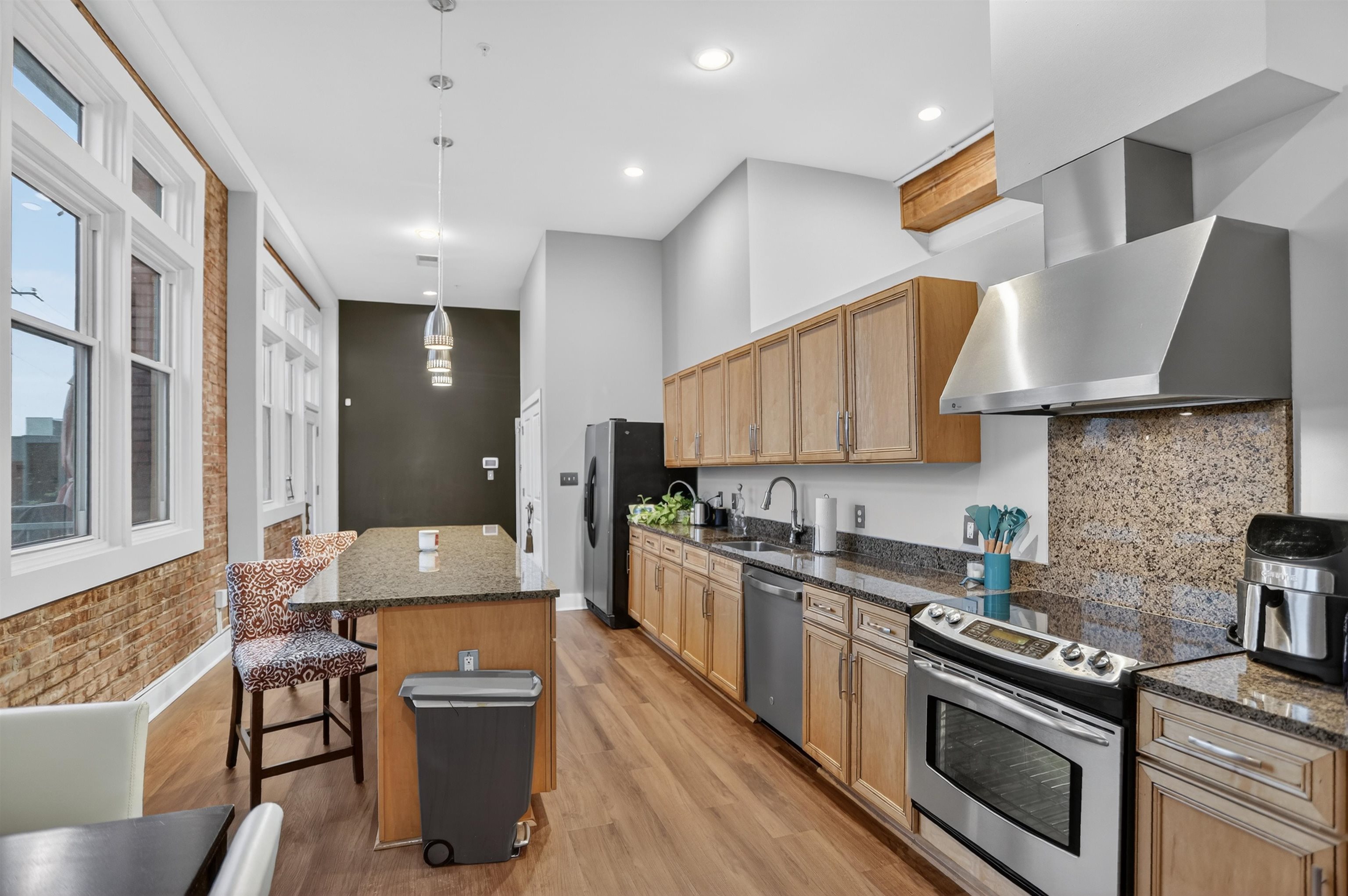 435 South Front Street, Unit 307 Memphis, TN 38103 - Photo 8 of 40 Kitchen with appliances with stainless steel finishes, a kitchen breakfast bar, a center island, wall chimney range hood, and dark stone countertops
