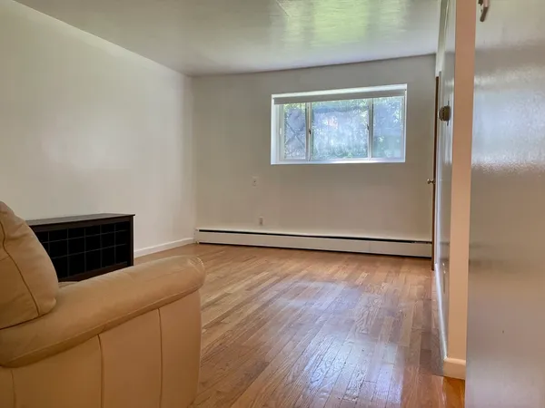 a view of an empty room with wooden floor and a window