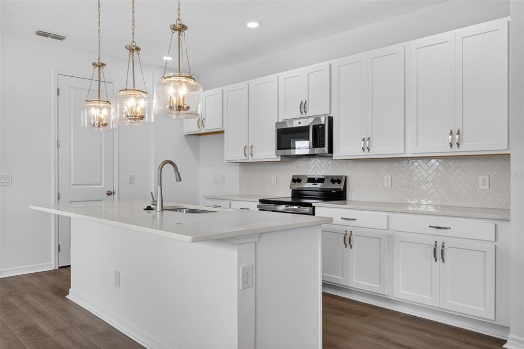 5777 Haystack Drive St. Cloud, FL 34771 - Photo 11 of 37 a kitchen with stainless steel appliances granite countertop a sink a microwave oven a refrigerator and white cabinets with wooden floor