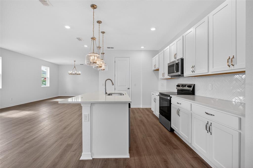 5777 Haystack Drive St. Cloud, FL 34771 - Photo 13 of 37 a kitchen with stainless steel appliances granite countertop a sink dishwasher a stove and white cabinets with wooden floor