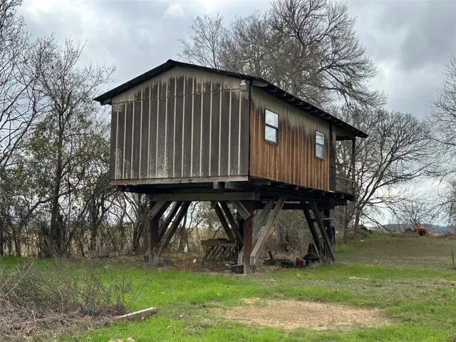 a front view of house with yard and trees all around
