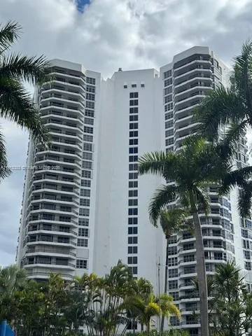 a front view of a building with plants and palm trees