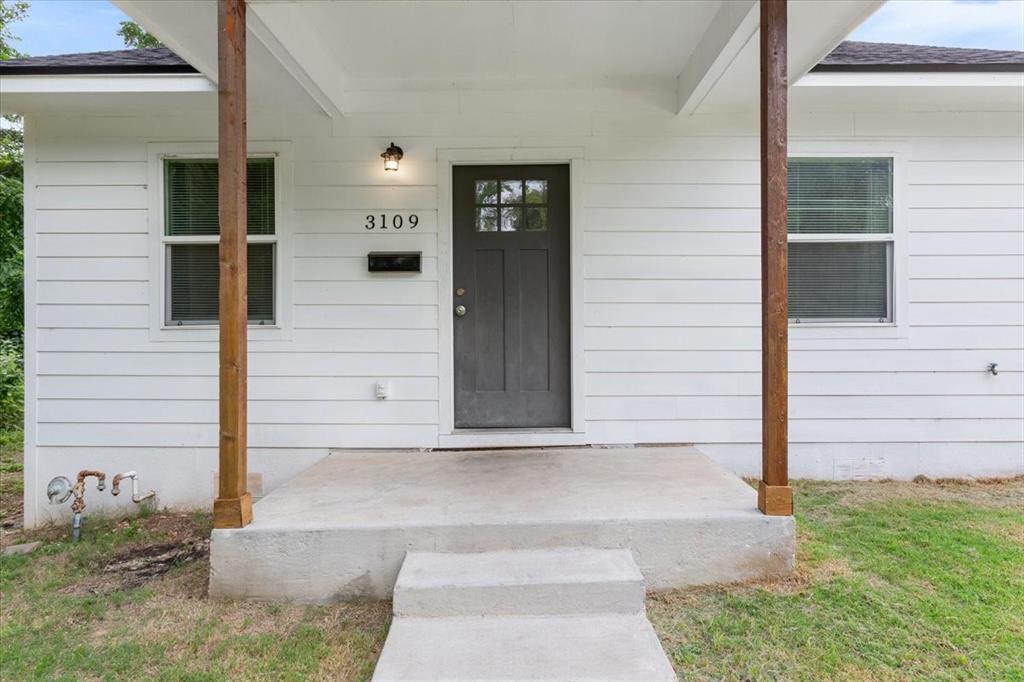 3109 North 20th Street Waco, TX 76708 - Photo 3 of 24 White horizontal siding exterior with a dark gray entry door featuring glass panes