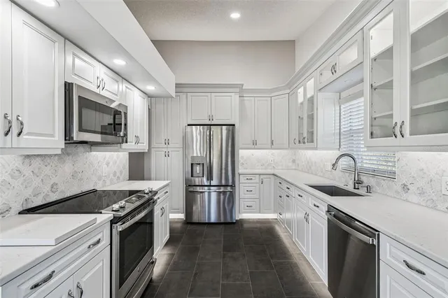 a kitchen with stainless steel appliances granite countertop a sink stove microwave and refrigerator
