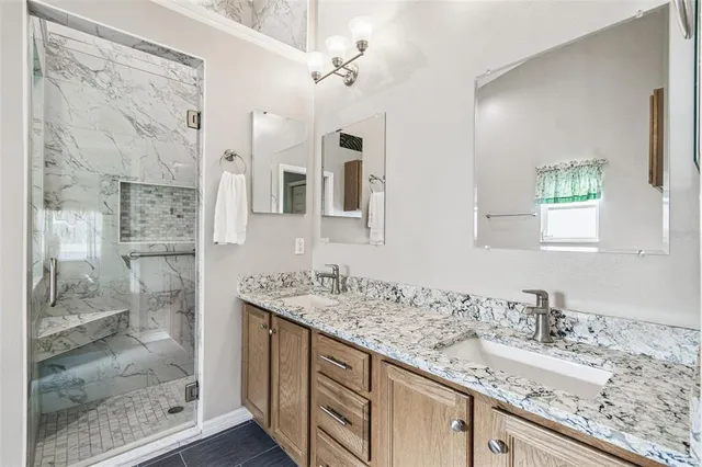 a bathroom with a granite countertop sink a mirror and shower