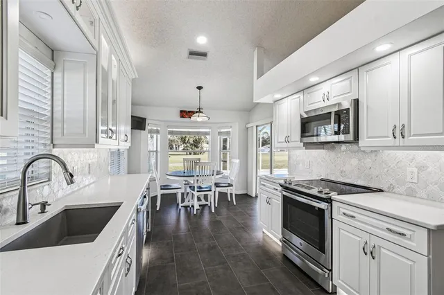 a kitchen with granite countertop a sink a counter space appliances and cabinets