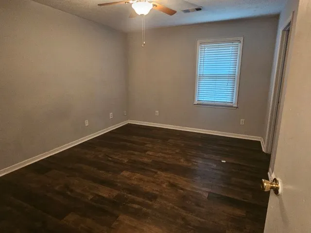 a view of room with hardwood floor and a ceiling fan