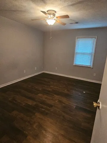 an empty room with wooden floor and chandelier fan