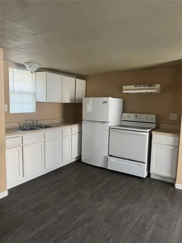 a kitchen with granite countertop white cabinets and white appliances