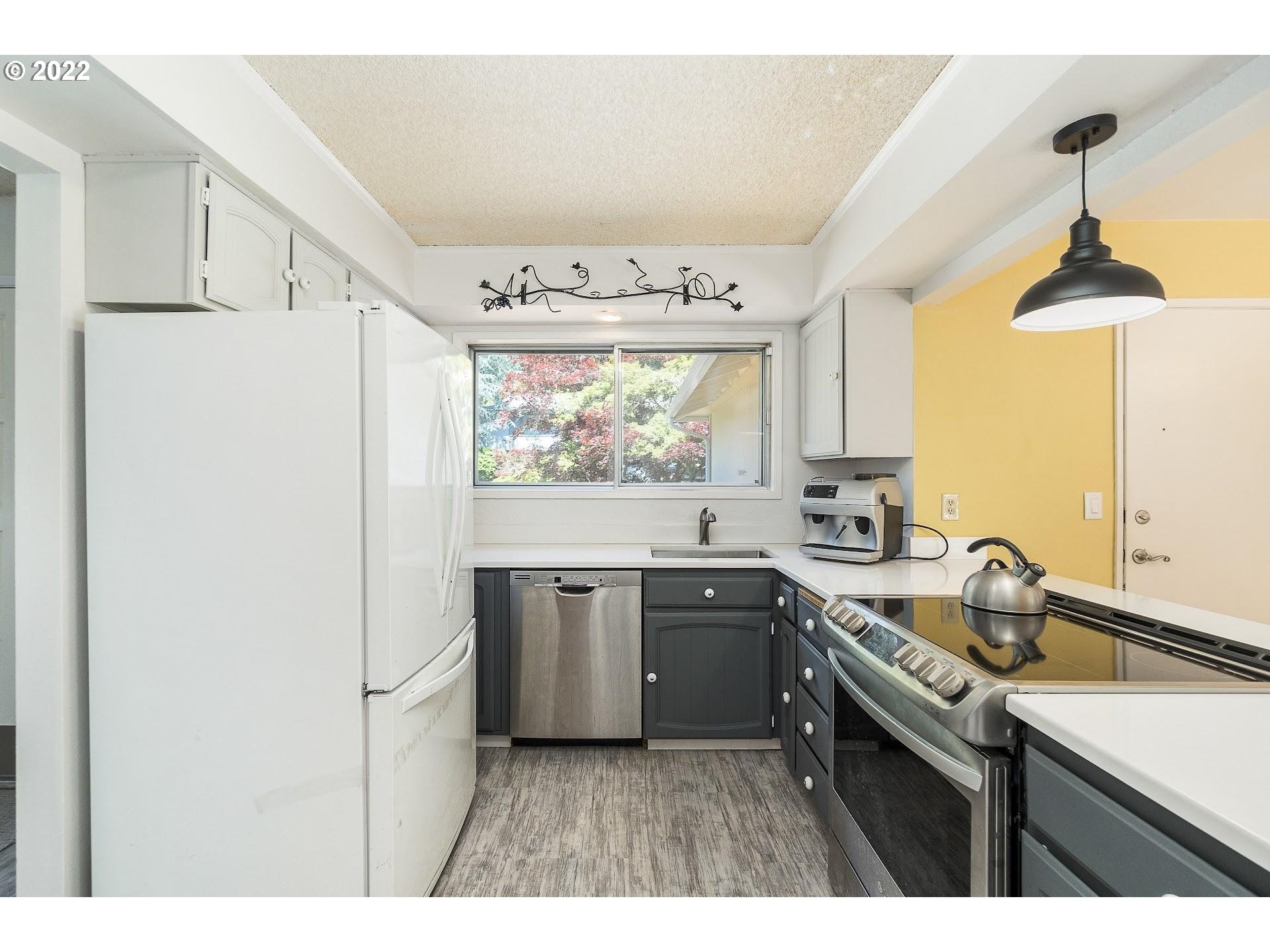 10880 Southwest Pathfinder Way Tigard, OR 97223 - Photo 12 of 26 a kitchen with a sink a stove a refrigerator and cabinets