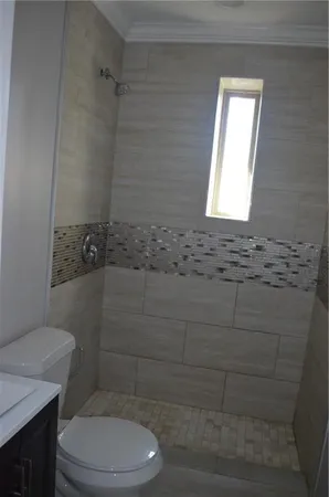 a bathroom with a toilet a sink a window and shower
