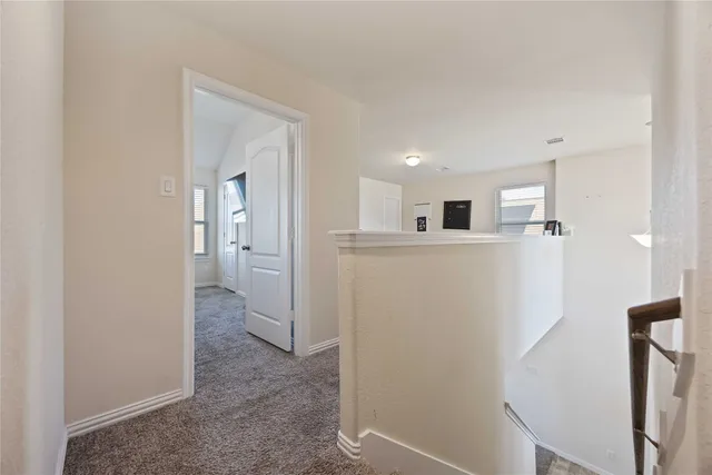 a view of a hallway with an empty room and wooden floor