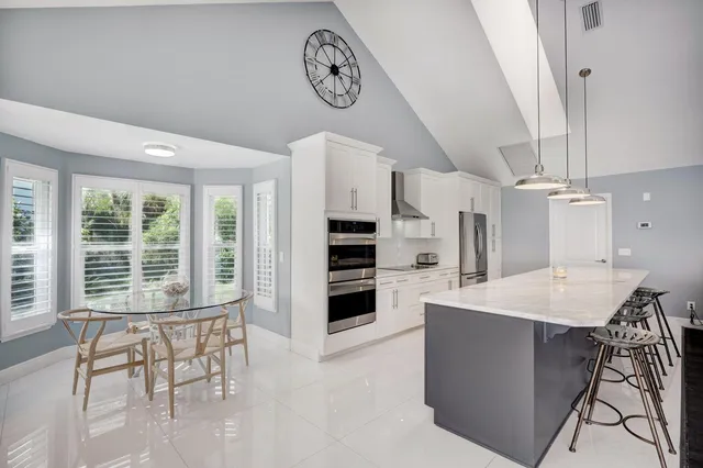 a large white kitchen with a large island a stove a sink and a living room view