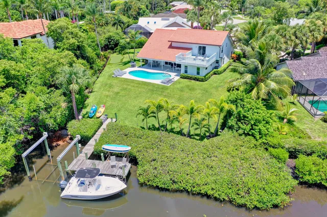 a aerial view of a house with swimming pool lawn chairs and a yard tree s