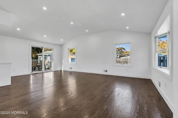 a view of empty room with wooden floor and window