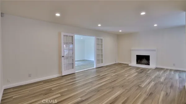 a view of an empty room with wooden floor and a fireplace