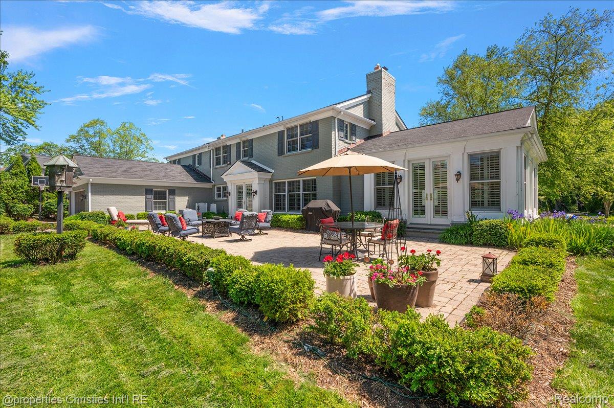 135 Clifton Road Bloomfield Hills, MI 48301 - Photo 76 of 77 Expansive paver patio bordered by manicured hedges, featuring a sunroom with French doors and window shutters