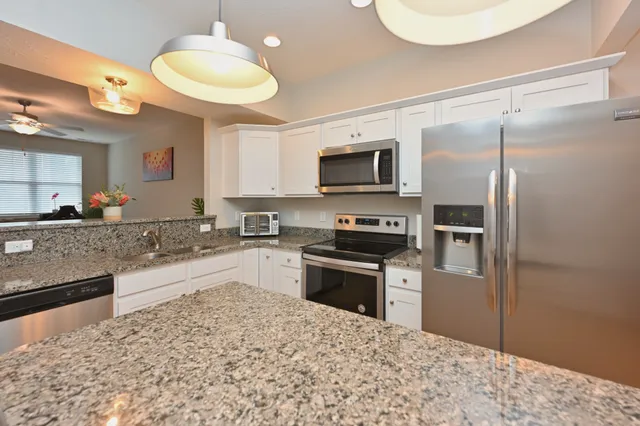a kitchen with stainless steel appliances granite countertop a sink refrigerator stove microwave and cabinets