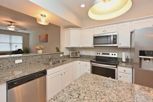 a kitchen with stainless steel appliances granite countertop a stove top oven a sink dishwasher and a microwave oven with cabinets