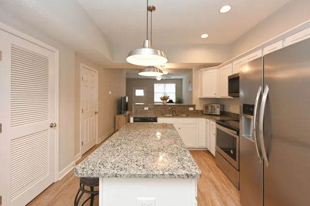 a large kitchen with kitchen island granite countertop a large counter top and stainless steel appliances