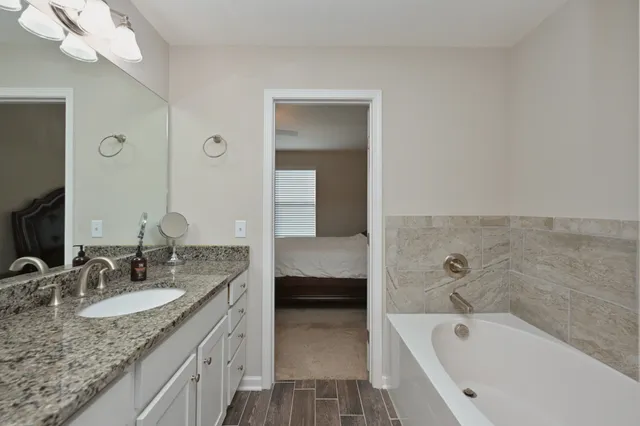 a bathroom with a granite countertop tub sink and mirror