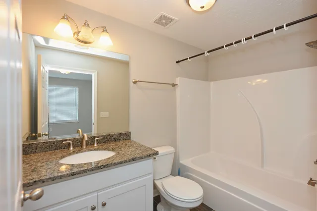 a bathroom with a granite countertop sink a toilet and a bathtub