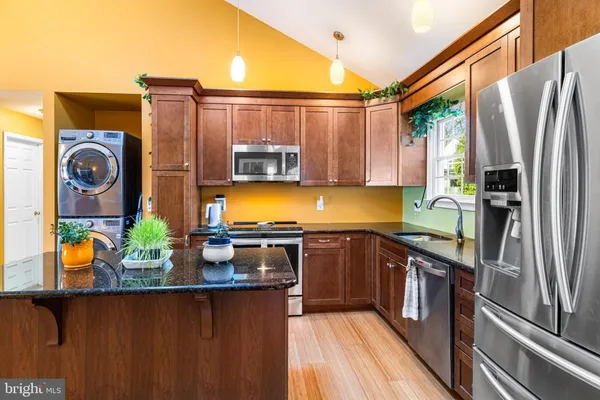 a kitchen with stainless steel appliances granite countertop a refrigerator a stove and a sink