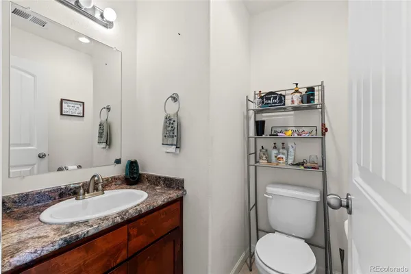 a bathroom with a granite countertop toilet sink and mirror