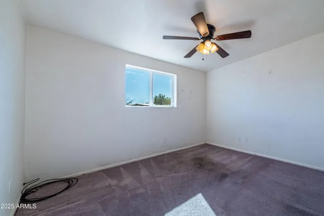 an empty room with a window and a fan