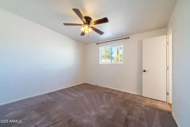 a view of an empty room with chandelier fan and a window